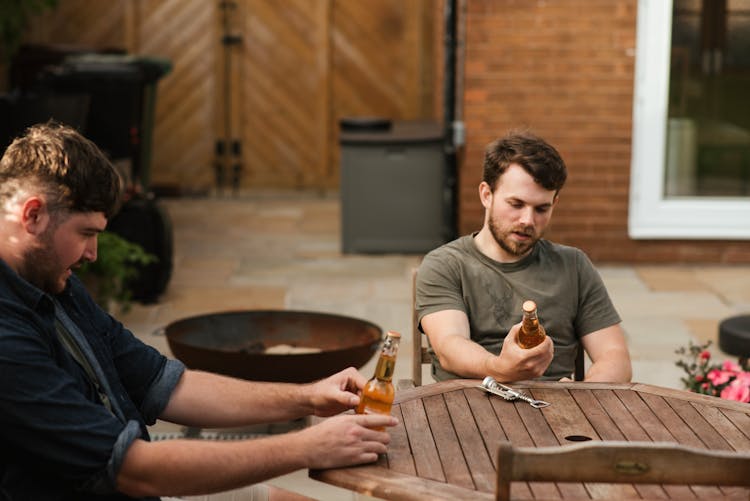 Friends Reading Beer Labels In Backyard