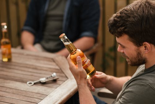 Man reading information written on glass bottle of beer