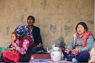 Woman in Red and White Floral Dress Sitting Beside Woman in Black and White Hijab