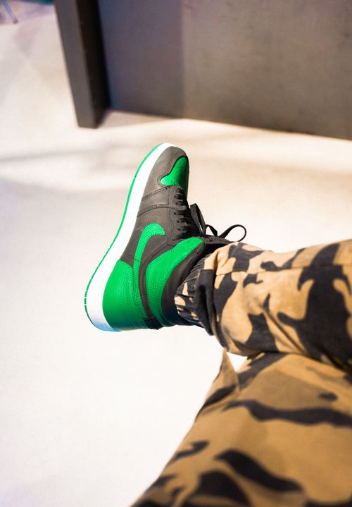 Free Close-up of stylish green and black sneaker with camouflage pants, showcasing modern fashion trends. Stock Photo
