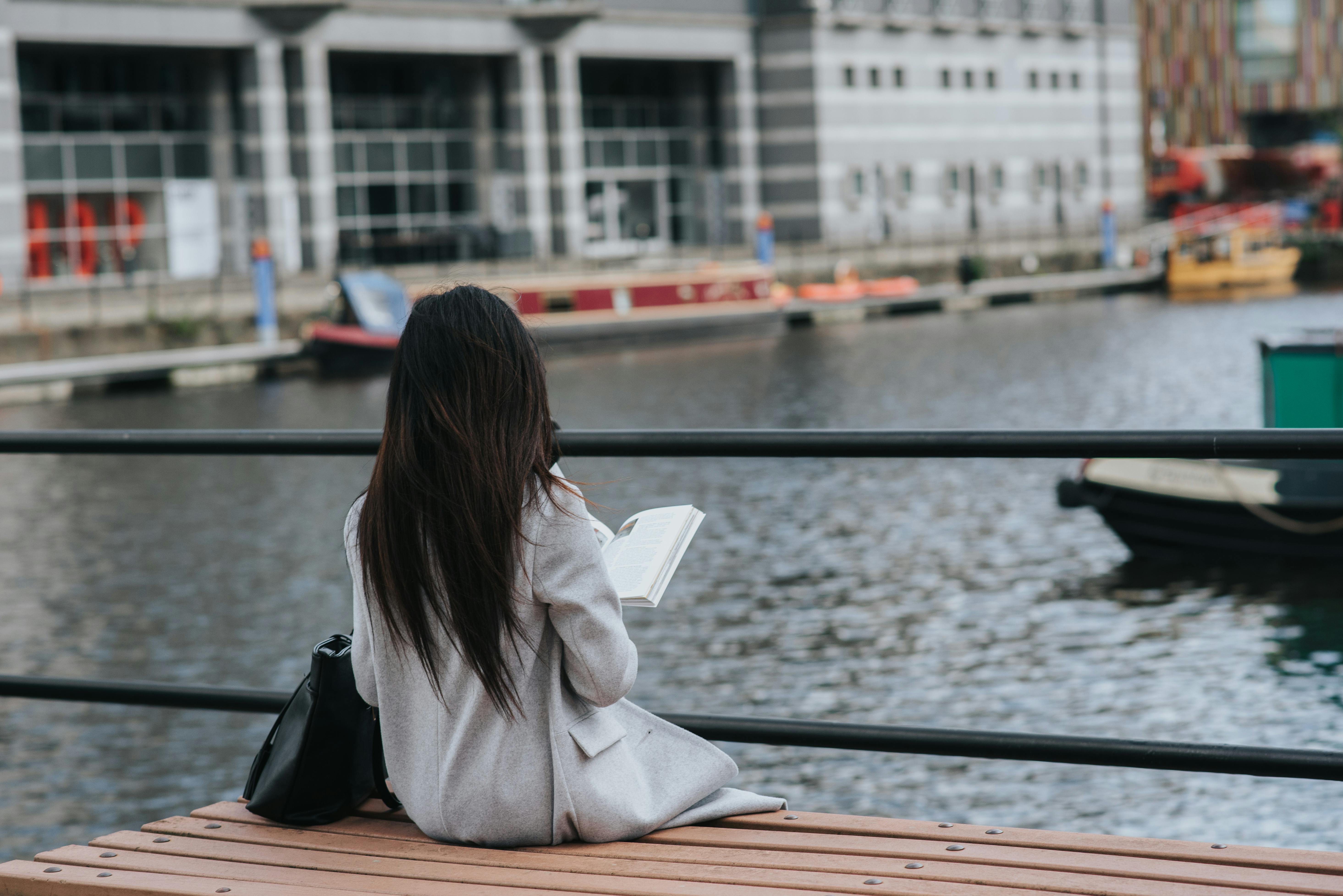 woman spending leisure on river bank with book