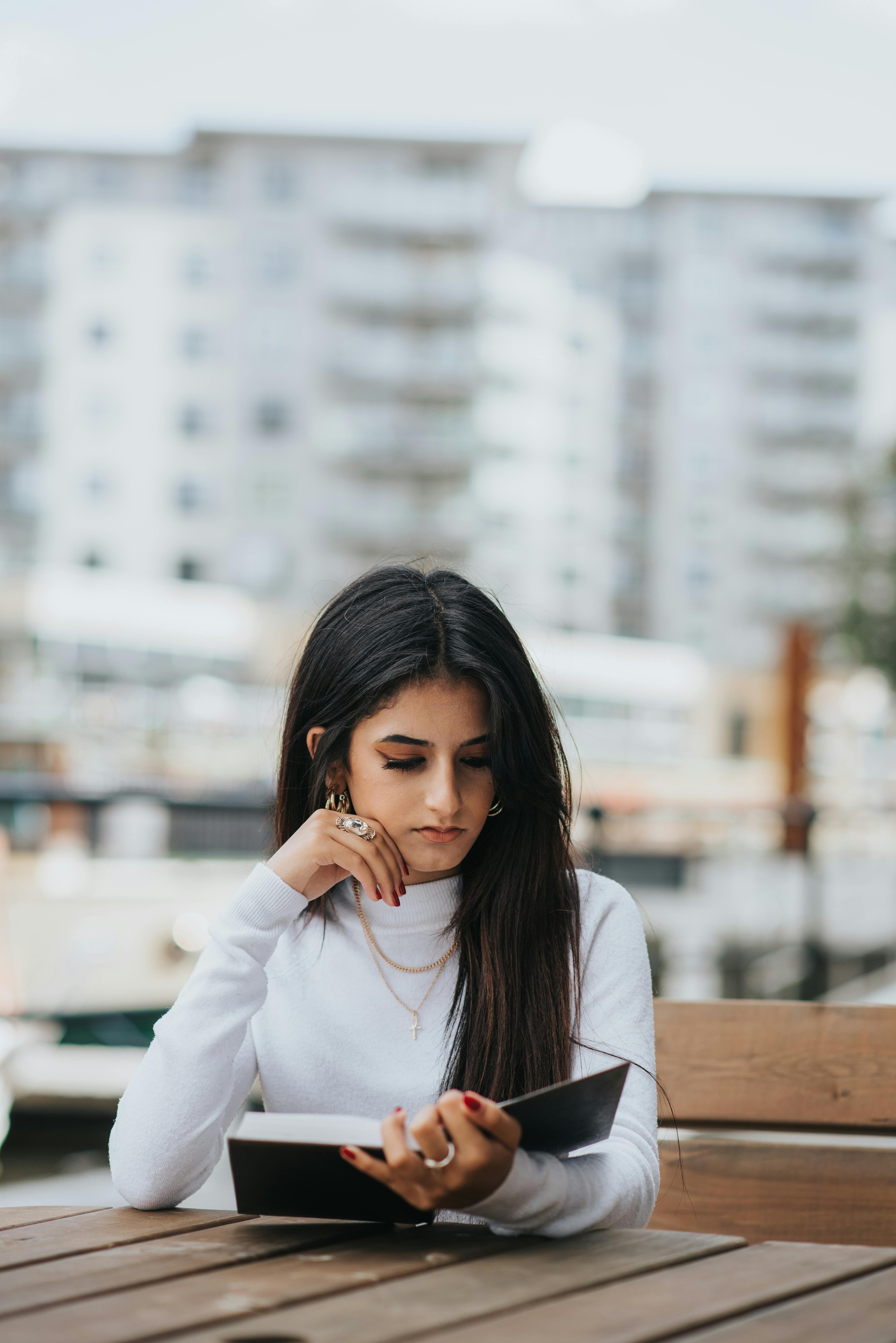 pensive ethnic woman reading book in cafe