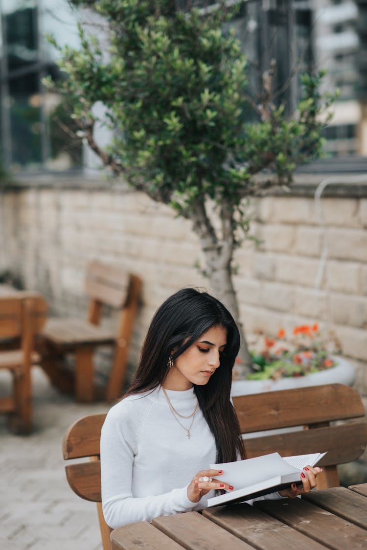 Young Ethnic Woman Turning Page Of Book