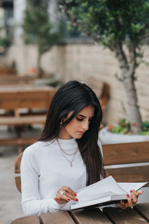 Серьезная этническая женщина читает дневник в летнем кафе