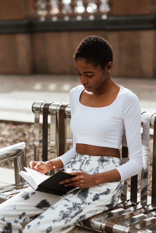 Free Pensive black woman reading book on bench Stock Photo