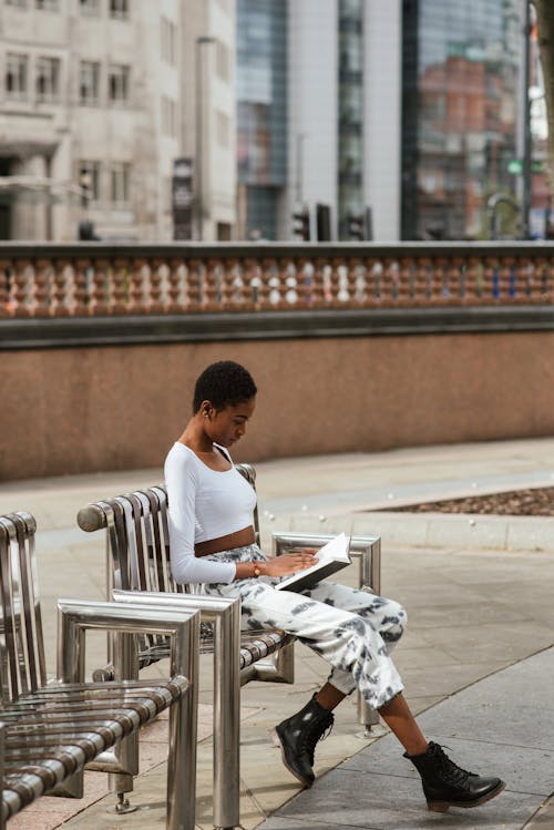 Black woman reading textbook on urban bench