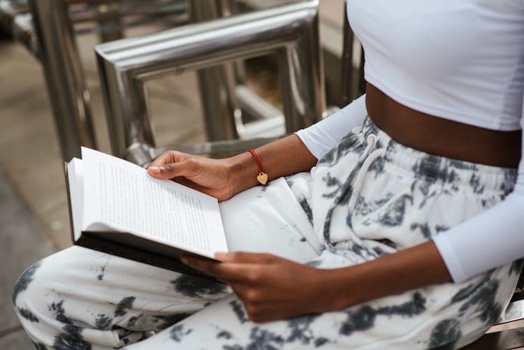 Crop Black Woman Reading Book On Street Bench