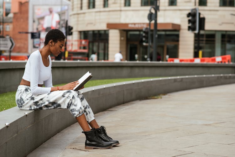 Attentive Black Woman Reading Book On City Street