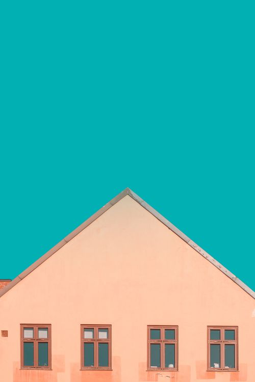 Free Peach house facade with triangular roof against a vivid teal sky in Oslo. Stock Photo