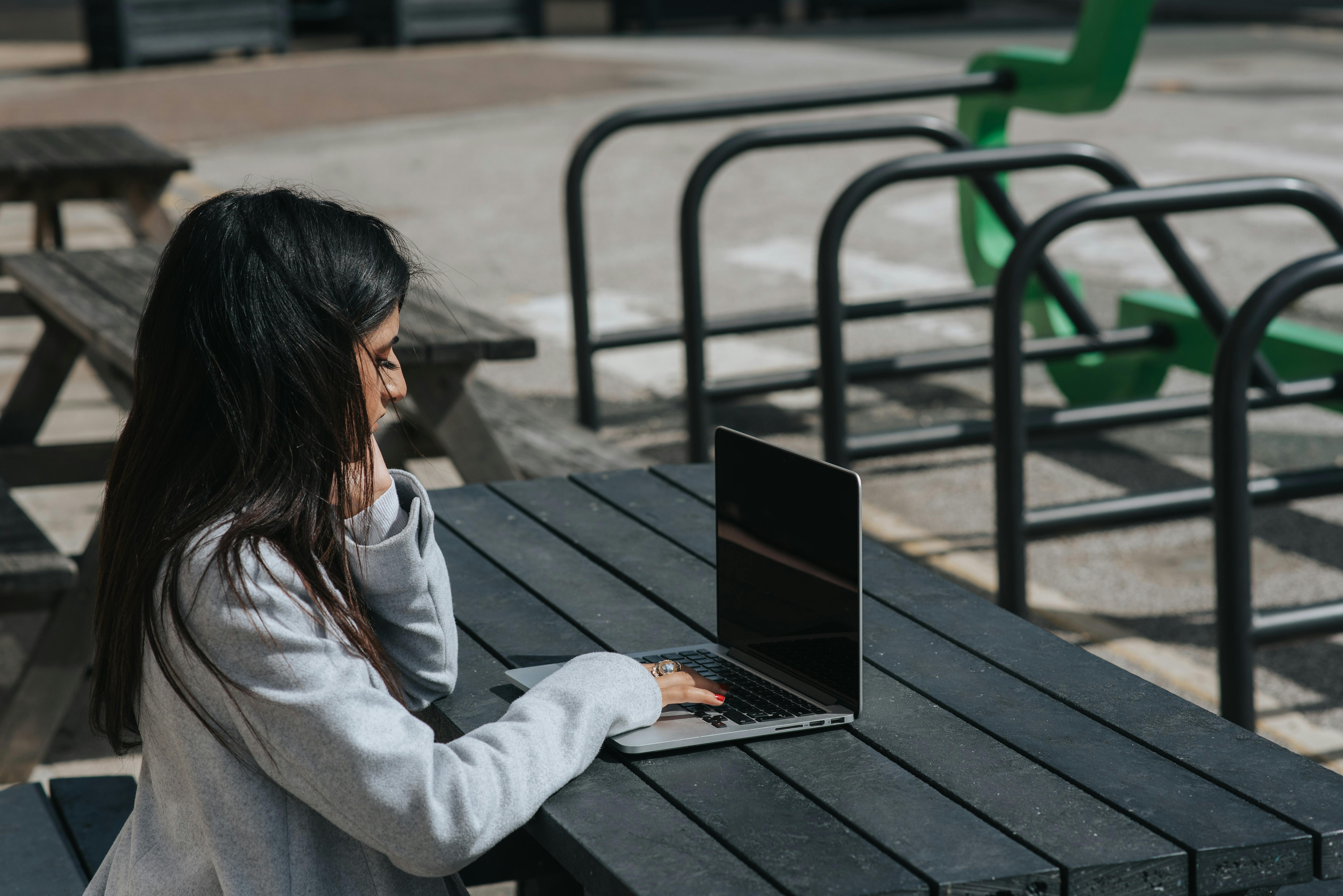 ethnic businesswoman working on laptop at street table