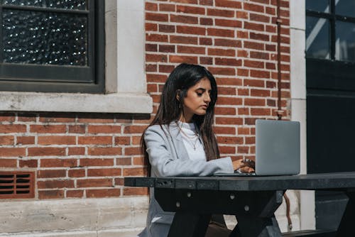 Pengusaha Perempuan Etnik Yang Penuh Perhatian Sedang Mengetik Di Laptop Di Kota