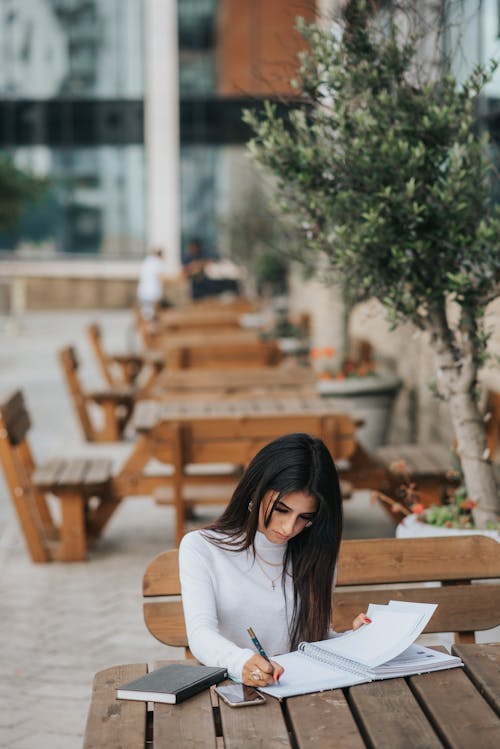 Trabalhador étnico Concentrado Escrevendo Em Um Caderno Na Mesa Do Café