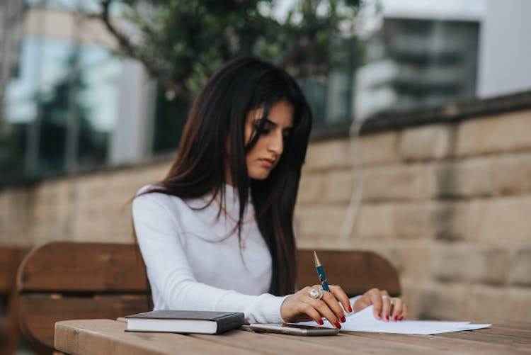 Thoughtful Ethnic Office Worker With Papers At Street Table