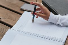 From above of crop anonymous ethnic female entrepreneur with pen and notebook working at wooden table