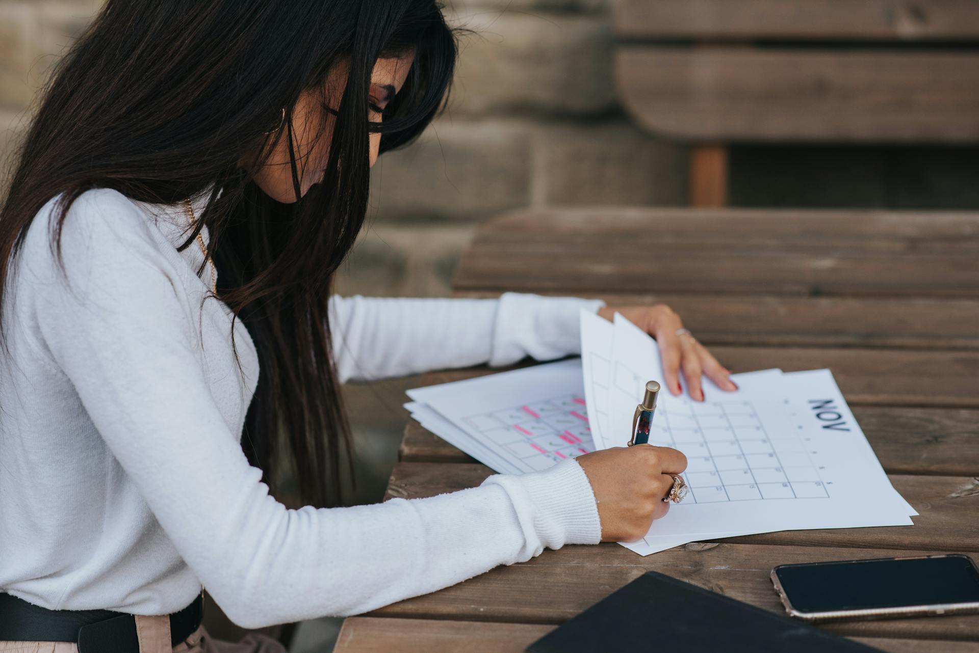 Crop ethnic office employee making schedule at table