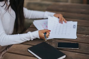 Side view of crop unrecognizable ethnic female office employee working with papers representing month plan