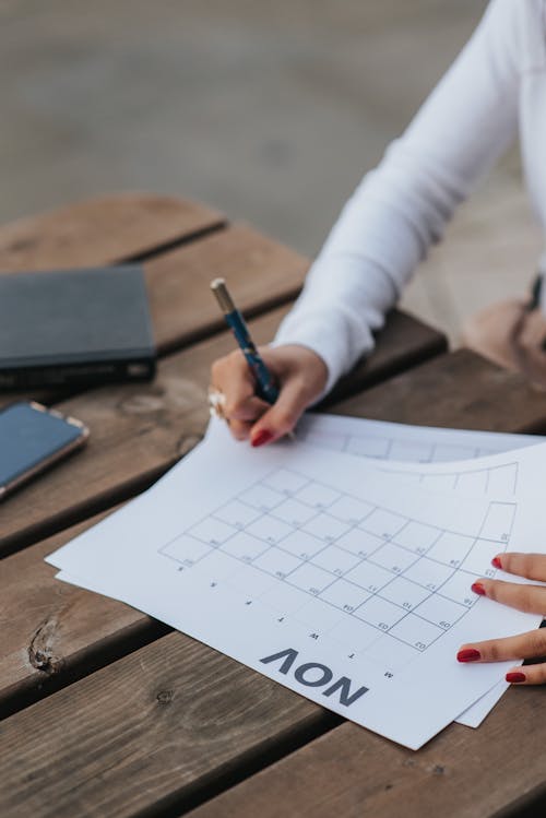 Free Crop woman making schedule in calendar Stock Photo