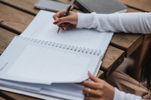 Free Crop woman making schedule in planner Stock Photo