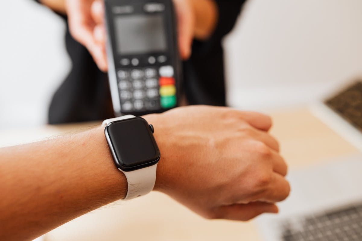 Polso con Apple Watch avvicinato a terminale per pagamento contactless in negozio