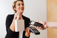 在现代商店中，收银员微笑着通过非接触式移动支付处理购买