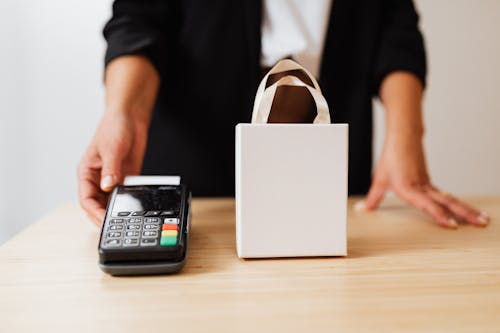 Free Person Holding Black Payment Terminal beside White Paper Bag Stock Photo