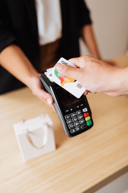 A person using a credit card for contactless payment at a retail counter. A person using a credit card for contactless payment at a retail counter.