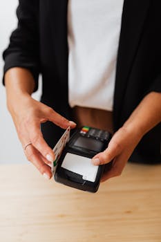 Close-up of hands using a credit card on a POS machine, illustrating cashless transactions.