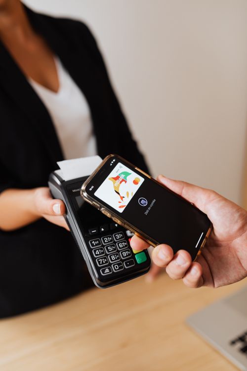 Ruka koja drži mobitel i plaća beskontaktno — simbolizira trenutačni digitalni transfer