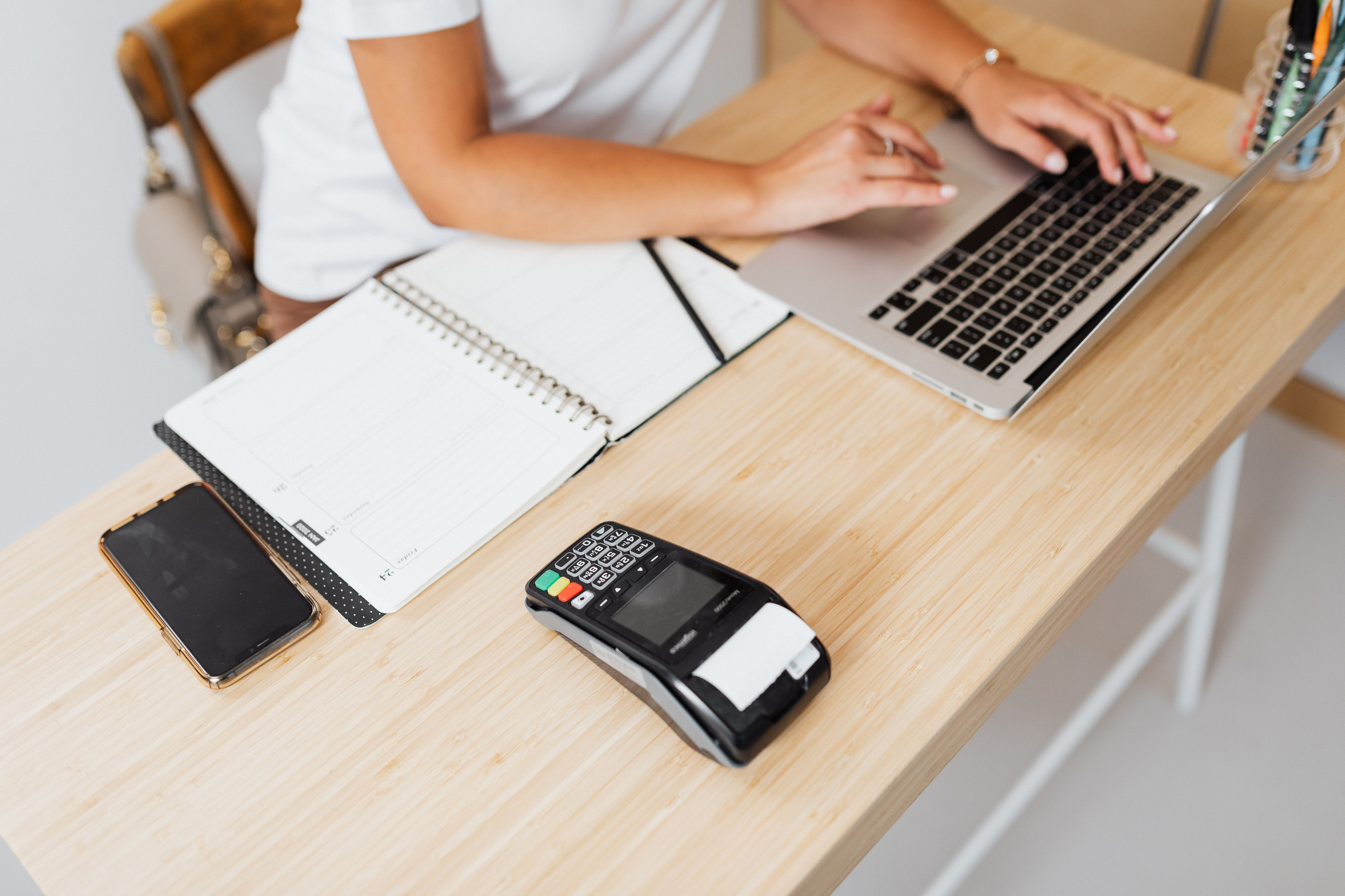 Modern workspace featuring a laptop and payment terminal setup on a wooden table.