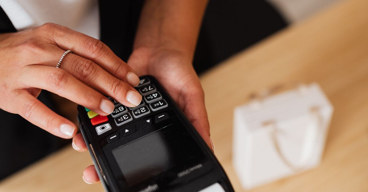 Rüyada Para Yığınına Dokunmak - Rüya Tabiri ve Anlamı - A person's hand using a card payment terminal, illustrating a cashless transaction.