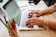 一个人坐在木桌前，用笔记本电脑打字，展现了高效的工作环境