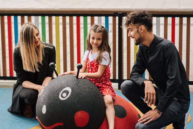 Family Sitting On Playground And Enjoying Each Other