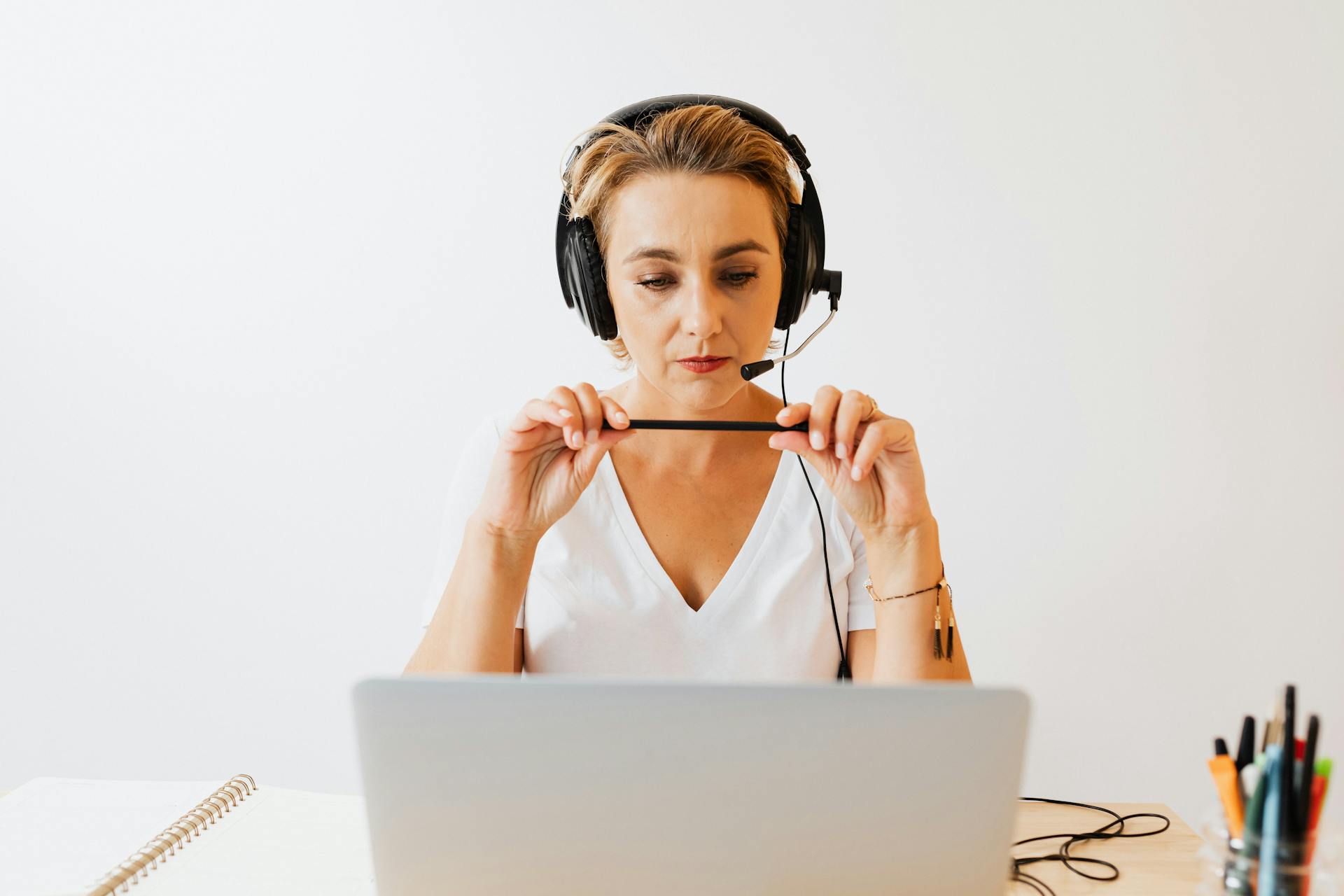 Adult woman in headphones using laptop for remote work in a home office setting.