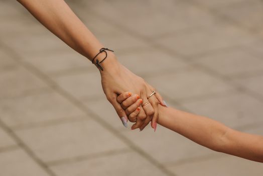 白天，一位戴着优雅订婚戒指的匿名女子牵着孩子的手走在街头