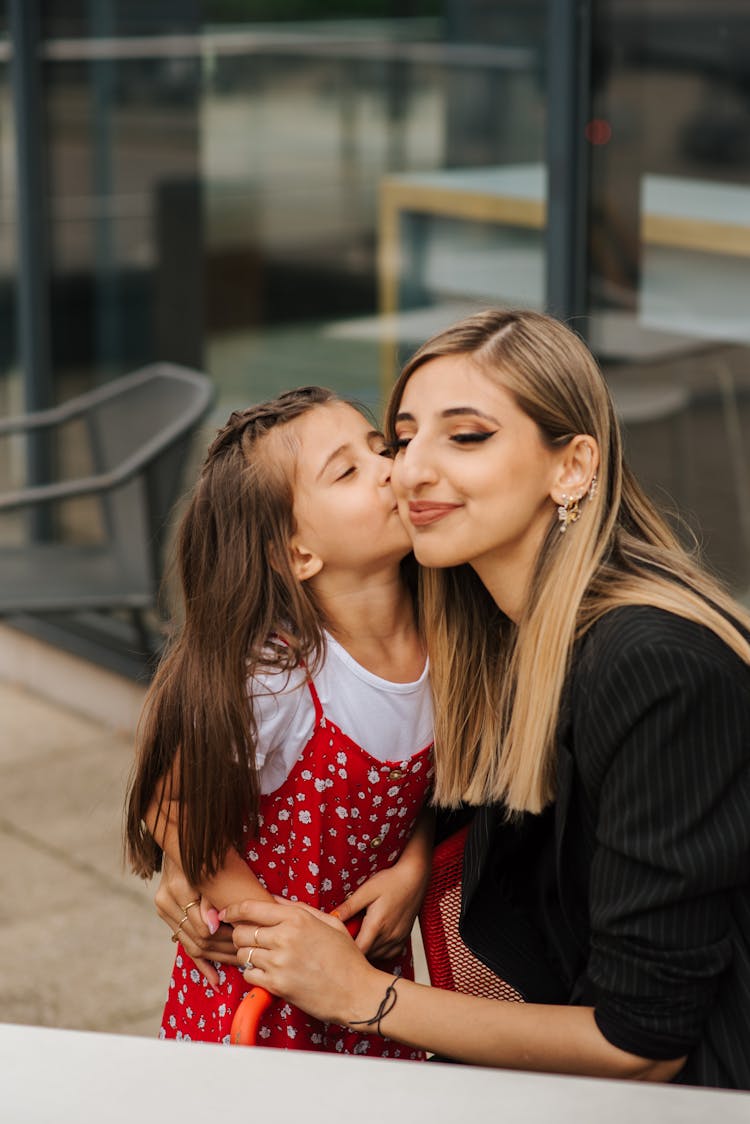 Daughter Giving Kiss To Mother On Street