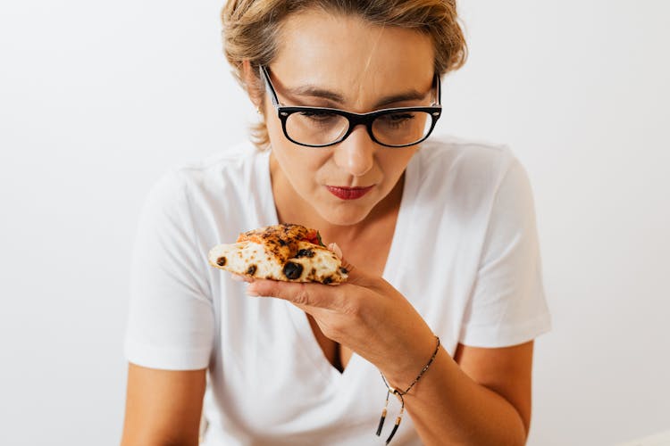 A Woman Holding A Slice Of Pizza