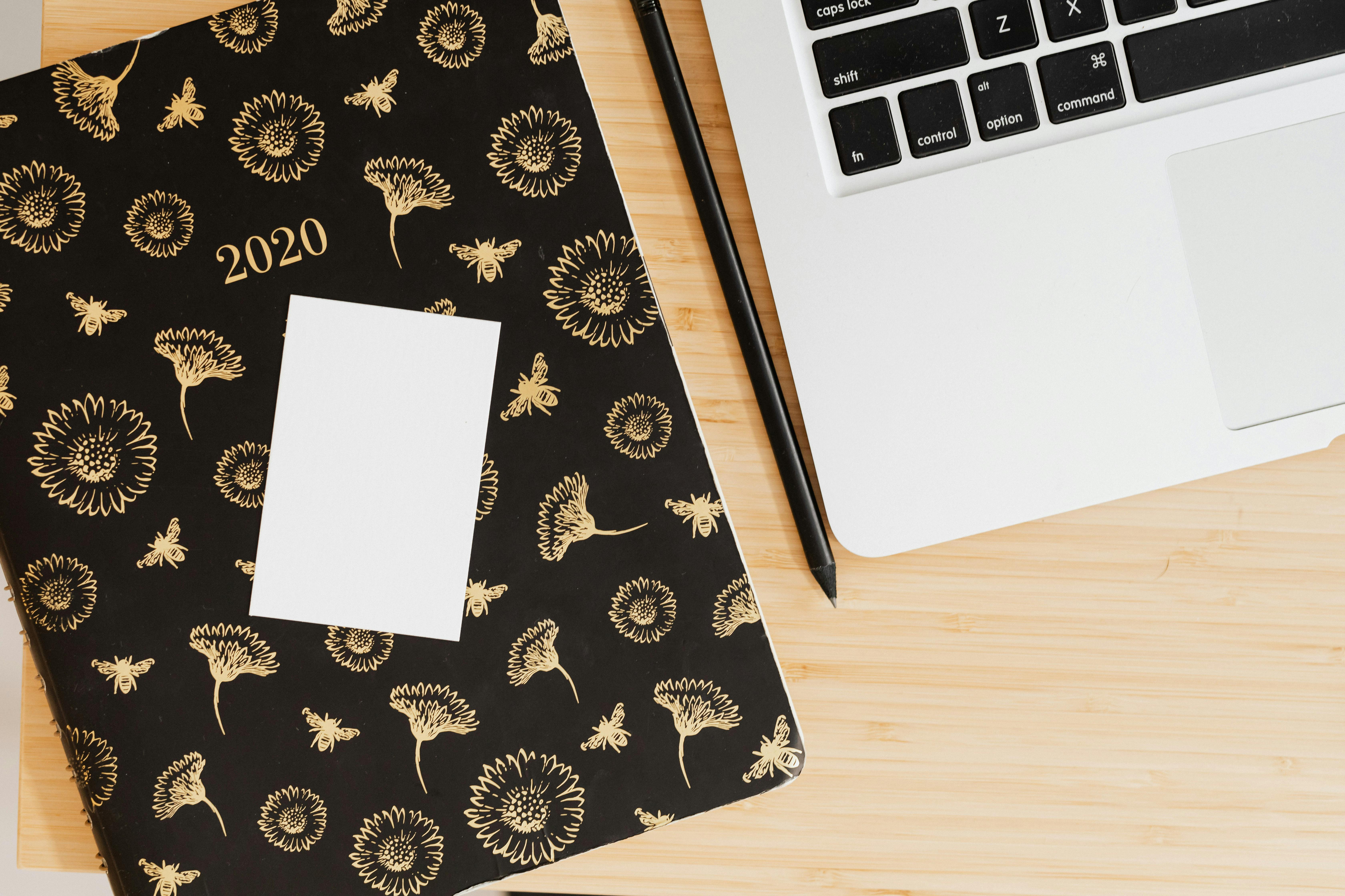 现代化工作空间的顶视图中，木桌上摆放着花卉规划师、笔和笔记本电脑