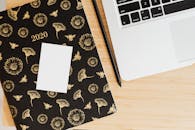 现代化工作空间的顶视图中，木桌上摆放着花卉规划师、笔和笔记本电脑