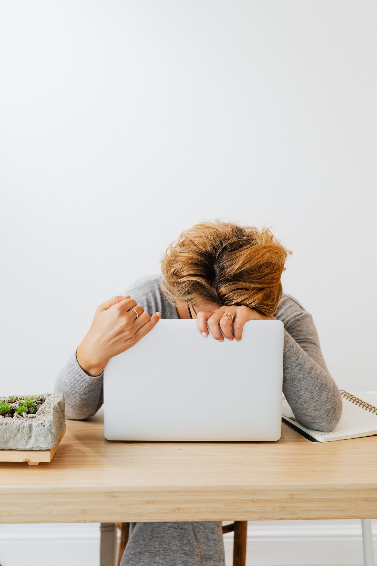 Woman resting her head on a laptop, exhausted at her desk