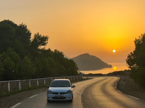Scenic road trip at sunset in Chlef, Algeria, with a car and golden sky.