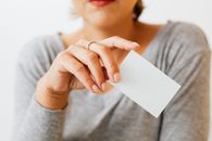 一位女士穿着灰色袖子，手里拿着一张空白名片，非常适合演示或实体模型使用