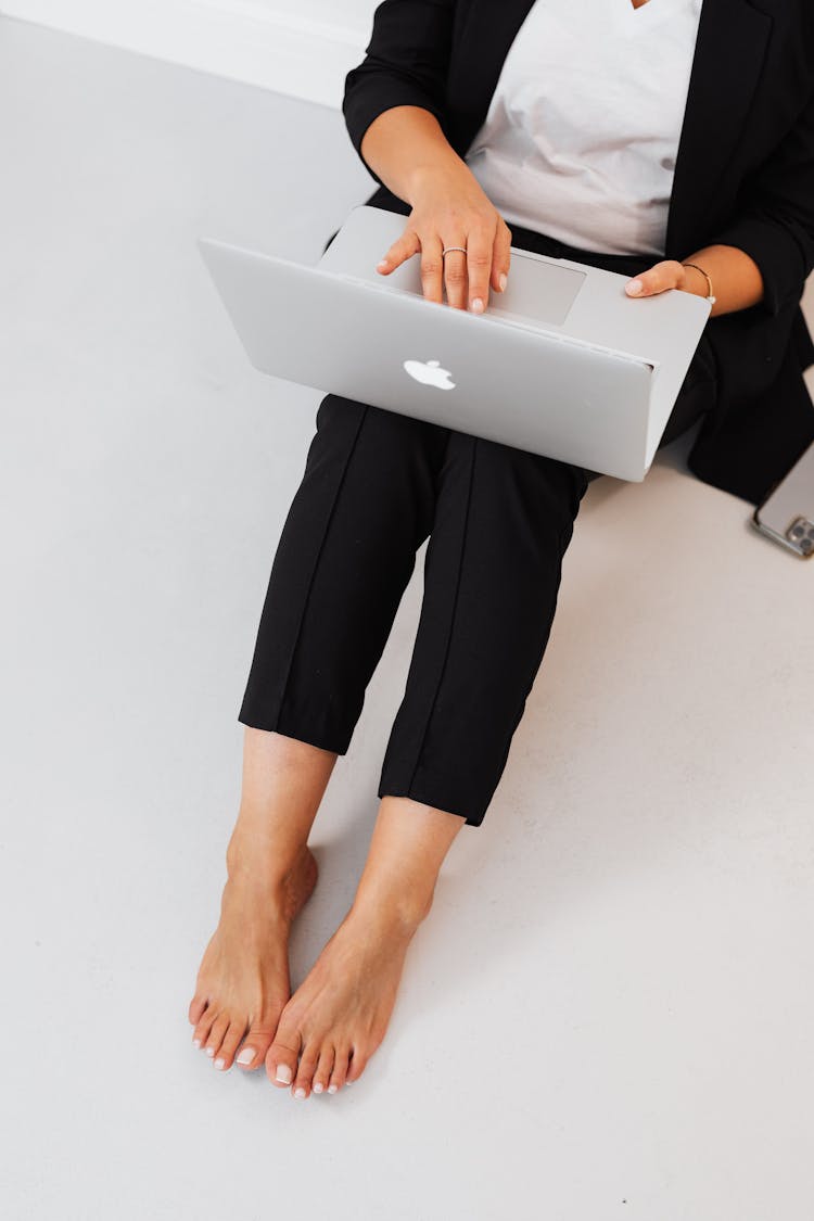 Person Sitting On Floor With Laptop On Her Knee