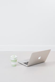 现代化的工作空间采用极简主义地板，并配有笔记本电脑和可折叠的环保杯