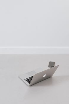 Stylish open laptop and smartphone on a minimalist floor, capturing modern work essentials.