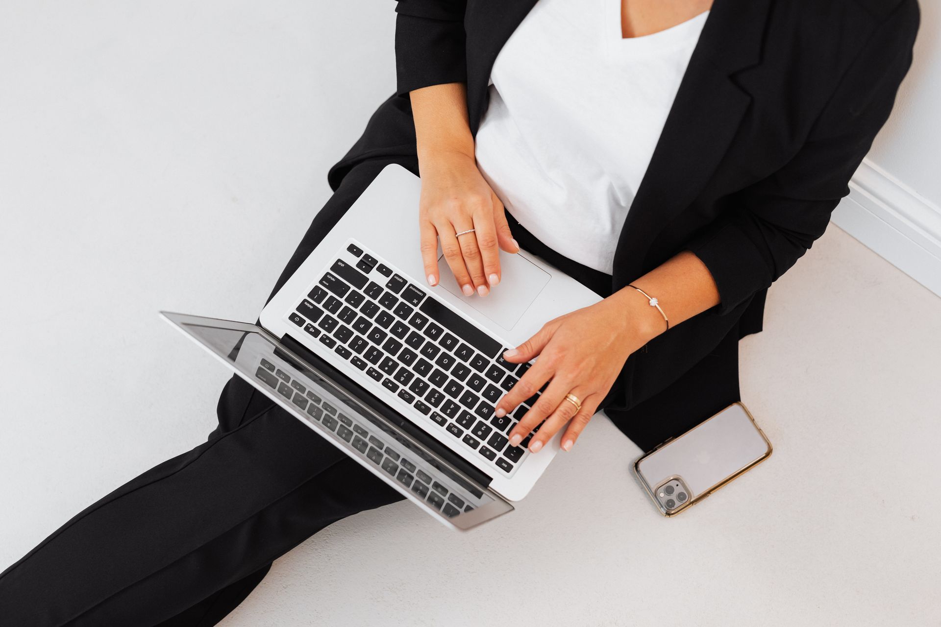 A Person in Black Blazer Sitting on the Floor while Using MacBook