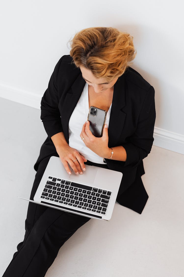 A Woman Sitting On The Floor Holding Iphone