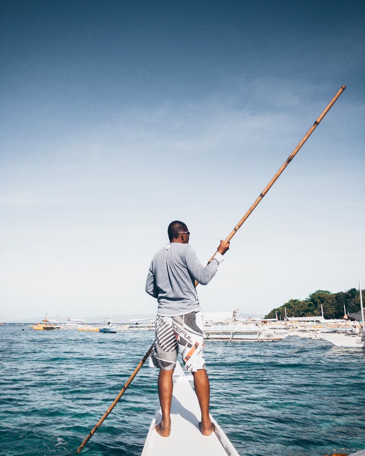 Man On The Boat Holding A Bamboo Pole