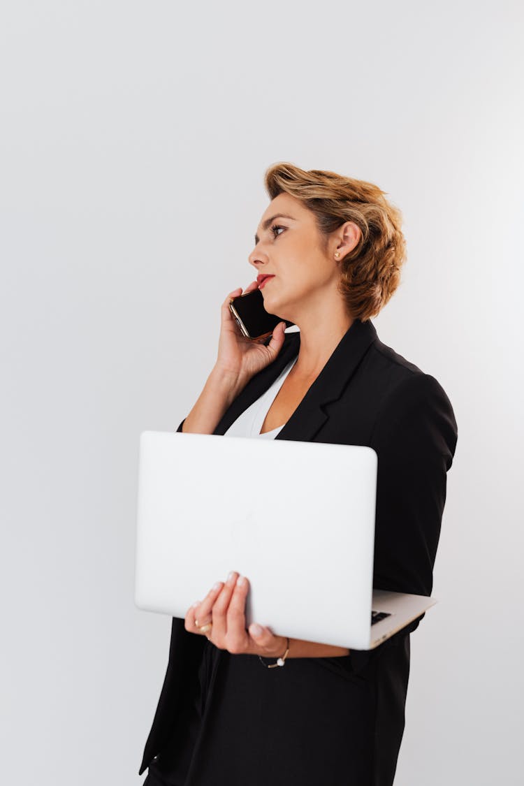 Woman Talking Over The Phone While Holding A Laptop