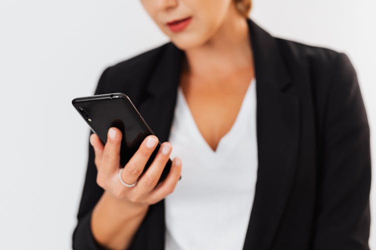 A Woman In Black Blazer Holding A Black Cellphone