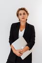 一位泰然自若的女商人，身穿黑色西装外套，手持笔记本电脑，以白色背景为衬托的肖像